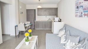 Ein kompakter Wohnraum mit Küchenzeile, Essbereich und Sofa.