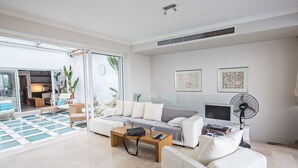 A spacious living room with a sofa, coffee table, and TV. There is a sliding glass door leading to a balcony with outdoor furniture. - Geräumige Ferienvilla mit atemberaubendem Ausblick by Interhome (Protaras)