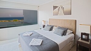 A modern bedroom with a large bed, a view of the ocean, and a painting of a pier. - Geräumige Ferienvilla mit atemberaubendem Ausblick by Interhome (Protaras)