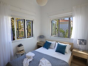 Une chambre à coucher avec un lit, deux tables de chevet, une lampe et une fenêtre avec des rideaux.