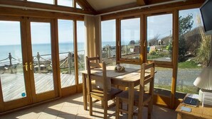 A wooden dining area with a view of the sea through large windows. - Ferien Scheune mit Blick auf das Meer und den Strand by Interhome (Barmouth)