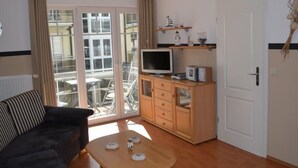 A living room with a sofa, a coffee table, a TV, and a wooden cabinet. - Rügenzauber in Ostseebad Baabe by Interhome (Baabe)