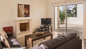 Ein Wohnzimmer mit Kamin, Fernseher, einer Couch und einem Esstisch.