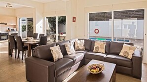 Ein modernes Wohnzimmer mit einer Eckcouch, einem Essbereich und einer Küche.