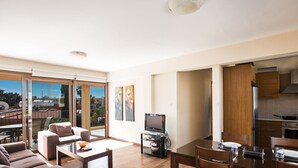 Ein modernes Wohnzimmer mit einer Sofagarnitur, einem Esstisch und einem Fernseher.