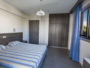 A bedroom with a bed, a wardrobe, a door, and a window with curtains. - Gemütliche Wohnung mit sch önem Balkon by Interhome (Ayia Napa)