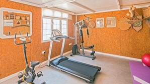 Un gimnasio en casa con cinta de correr, bicicleta estática y banco para pesas.