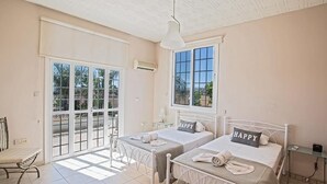 Ein Schlafzimmer mit zwei Betten, einem großen Fenster und einem Balkon.