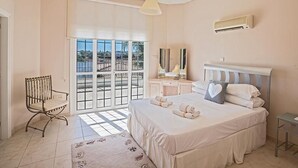 Un dormitorio con una cama grande, una silla, una mesita de noche y un ventanal con vistas.