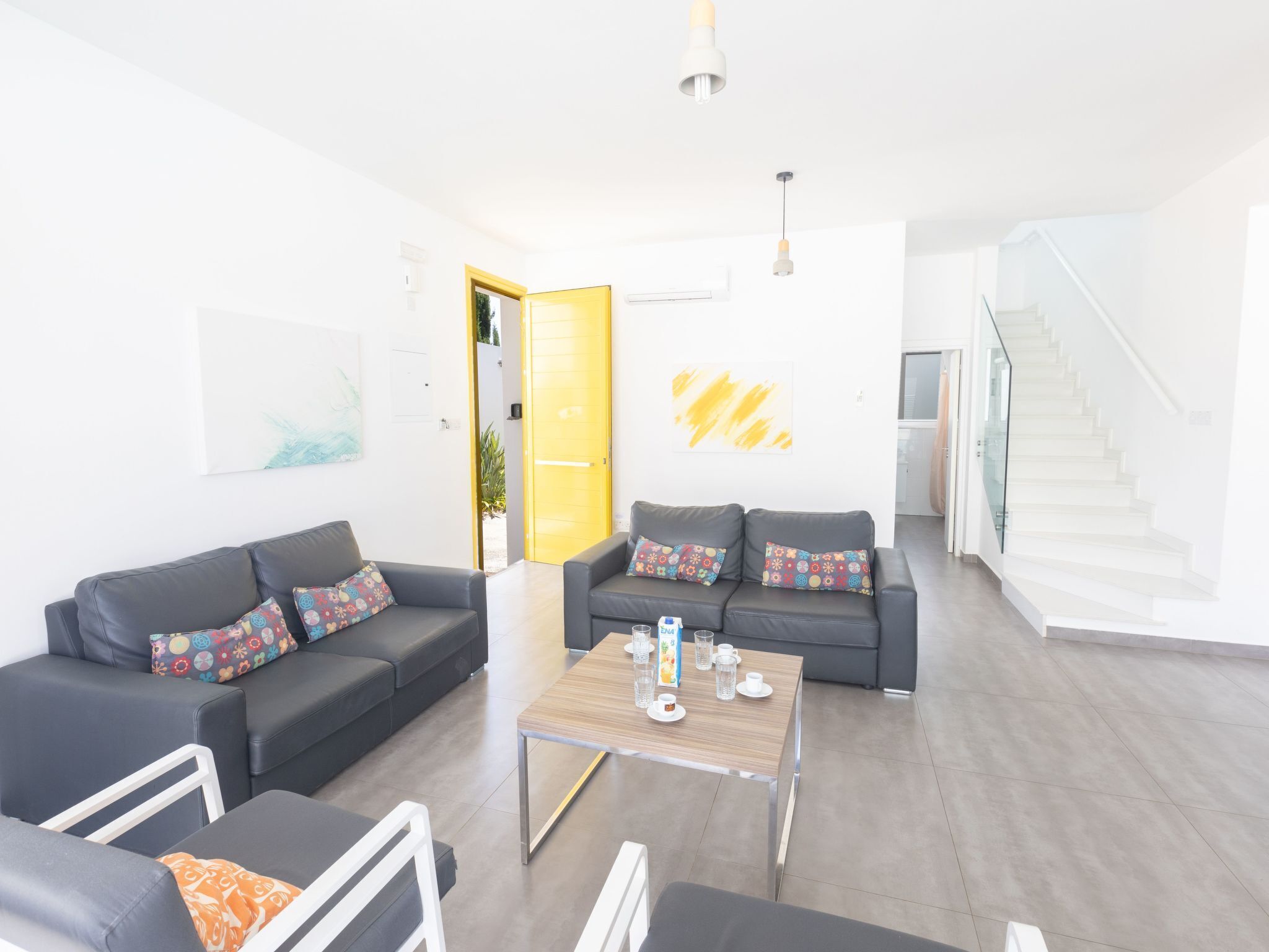 Ein modernes Wohnzimmer mit zwei Sofas, einem Couchtisch und einer Treppe.