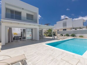 Een modern huis met twee verdiepingen, een zwembad, buitenterras en een overdekte patio.
