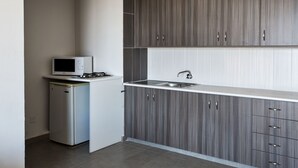 Eine moderne Küche mit grauen Schränken, einer eingebauten Mikrowelle und einer Spüle aus Edelstahl.