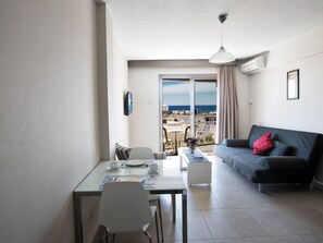 Un soggiorno moderno con zona pranzo, un divano grigio e un balcone con vista mare.