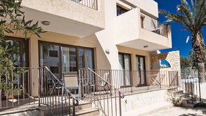 Ein modernes Gebäude mit einer Steinfassade, einem Balkon mit Metallgeländern und einer Treppe, die zum Eingang führt.