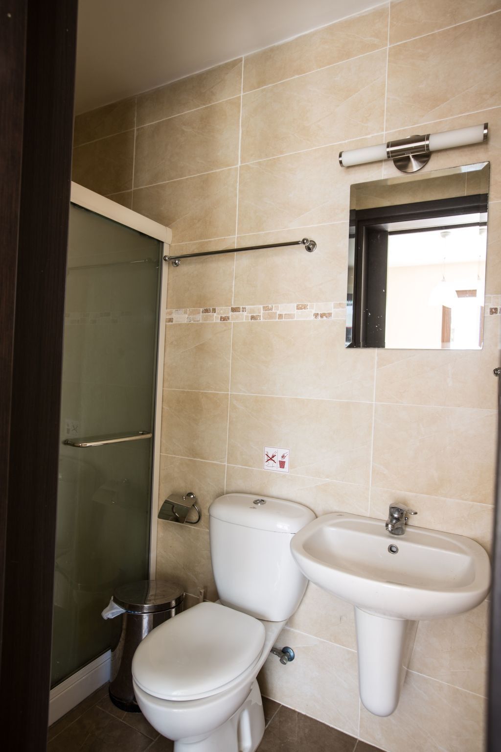 A bathroom with a toilet, sink, and glass shower door.