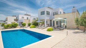 A modern villa with a swimming pool, outdoor seating, and a stone wall. - Latchi Ferienvilla EV26 by Interhome (Agios Georgios Pegeias)