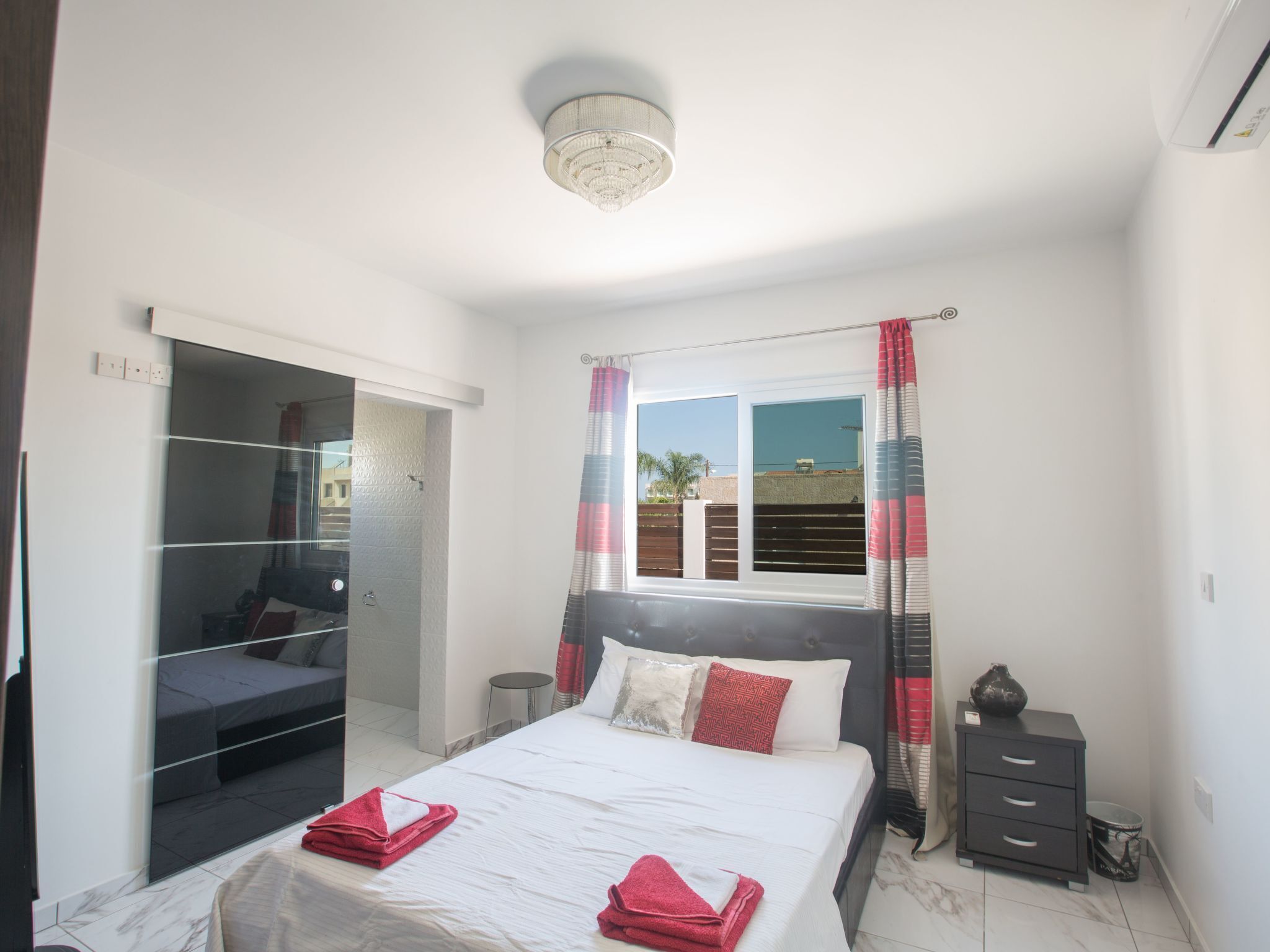 A bedroom with a bed, a wardrobe, a bedside table, and a window with curtains.