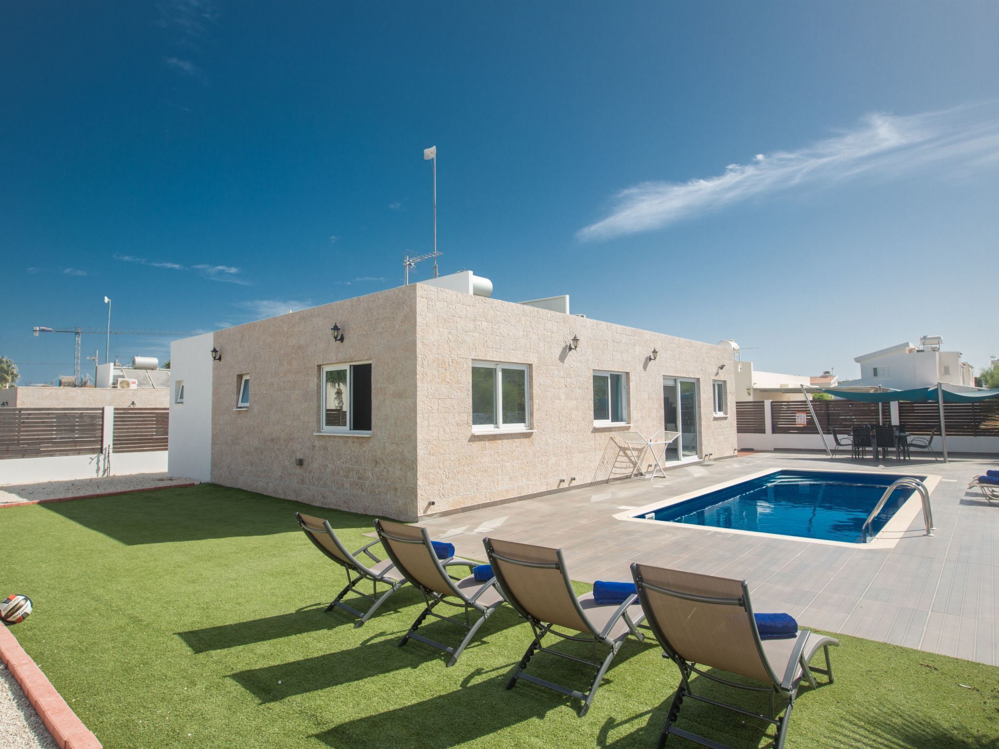 A modern building with a pool, outdoor seating, and a clear sky.