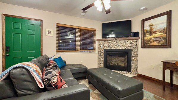 A living room with a fireplace, a green door, and a television.