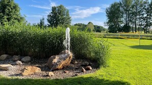 Una fontana in un giardino con un'area erbosa e alberi sullo sfondo.