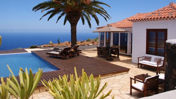 A pool area with lounge chairs, a dining table, and a view of the ocean. - Romantische Ferienvilla mit Infinity-Pool und Panoramameerblick by Interhome (Puntagorda)
