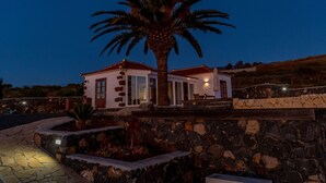 A stone-walled building with a palm tree in front, two white buildings with red roofs, and a stone pathway. - Romantische Ferienvilla mit Infinity-Pool und Panoramameerblick by Interhome (Puntagorda)