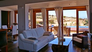 A spacious living room with a white sofa, a glass coffee table, and a view of the outdoors through large windows. - Romantische Ferienvilla mit Infinity-Pool und Panoramameerblick by Interhome (Puntagorda)