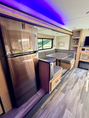 A compact RV interior with a kitchenette, seating area, and a small entertainment unit. - Perfect beach escape! Just yards away from the beach, pool, BBQ and near casinos (Rio Grande)