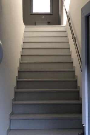A staircase with a handrail, leading to a landing with a window and a radiator. - "Schleie" direkt am Stausee by Interhome (Friesoythe)