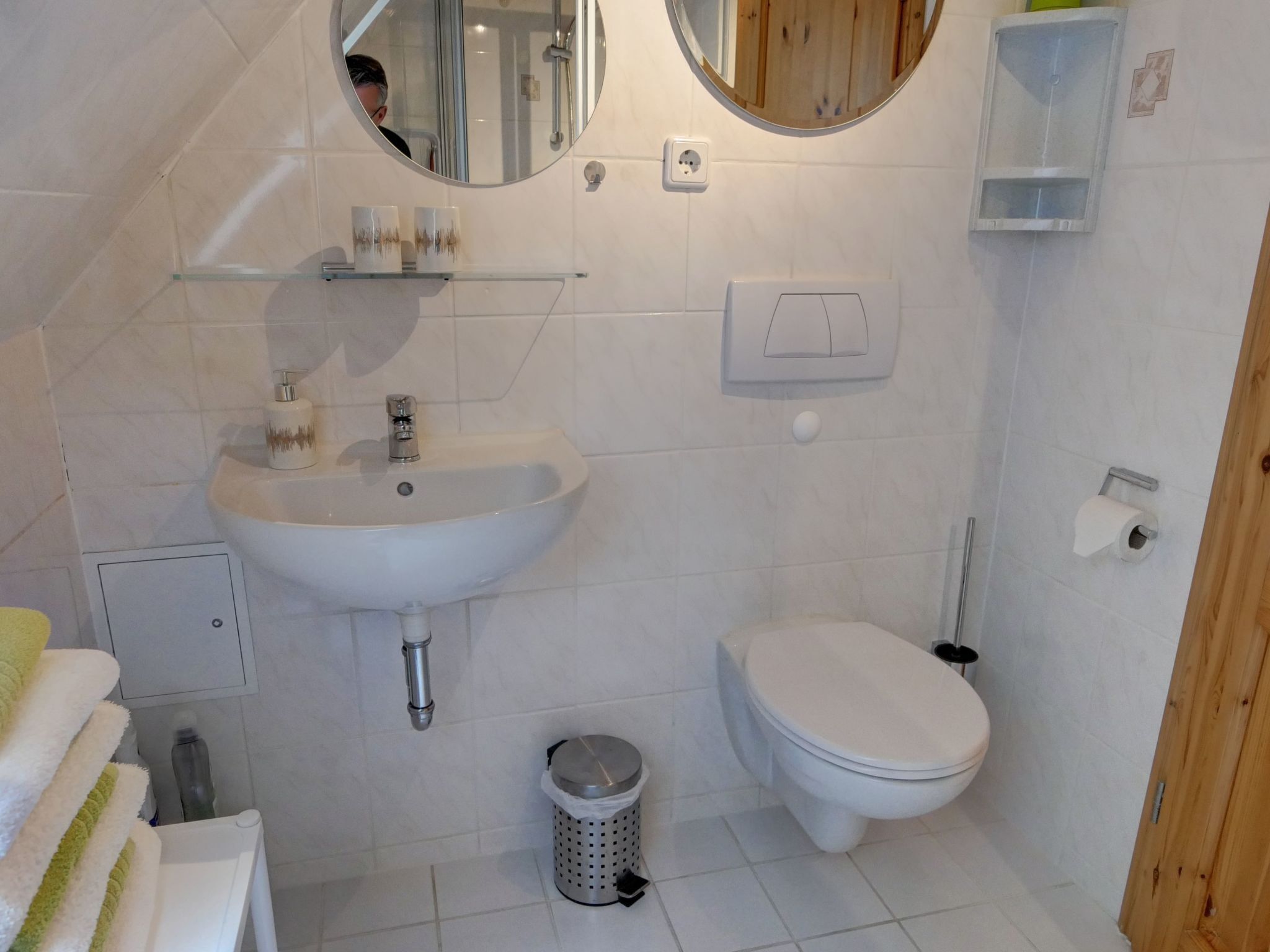 A bathroom with a sink, toilet, mirror, and a trash can.