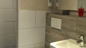 A modern bathroom with a toilet, sink, and mirror. - Apartment Oliver by Interhome (Fritzlar)