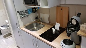 A modern kitchen with a stainless steel sink, a microwave, an induction cooktop, and a coffee machine. - Apartment Oliver by Interhome (Fritzlar)