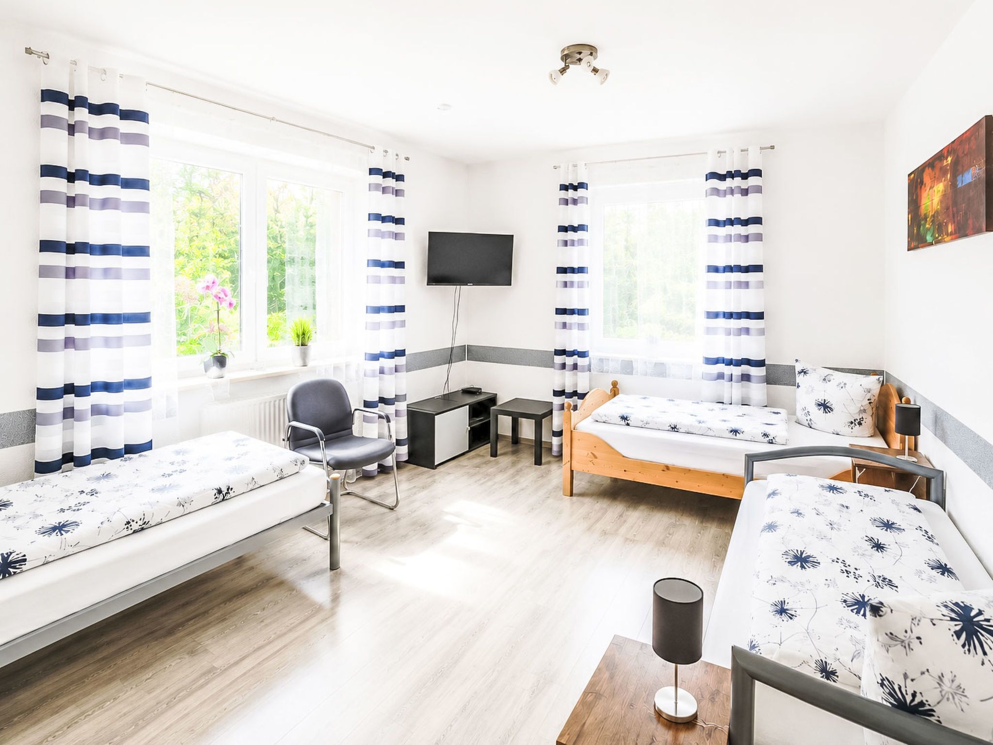 Een hotelkamer met twee bedden, een bureau, een stoel, een televisie en een raam met gordijnen.