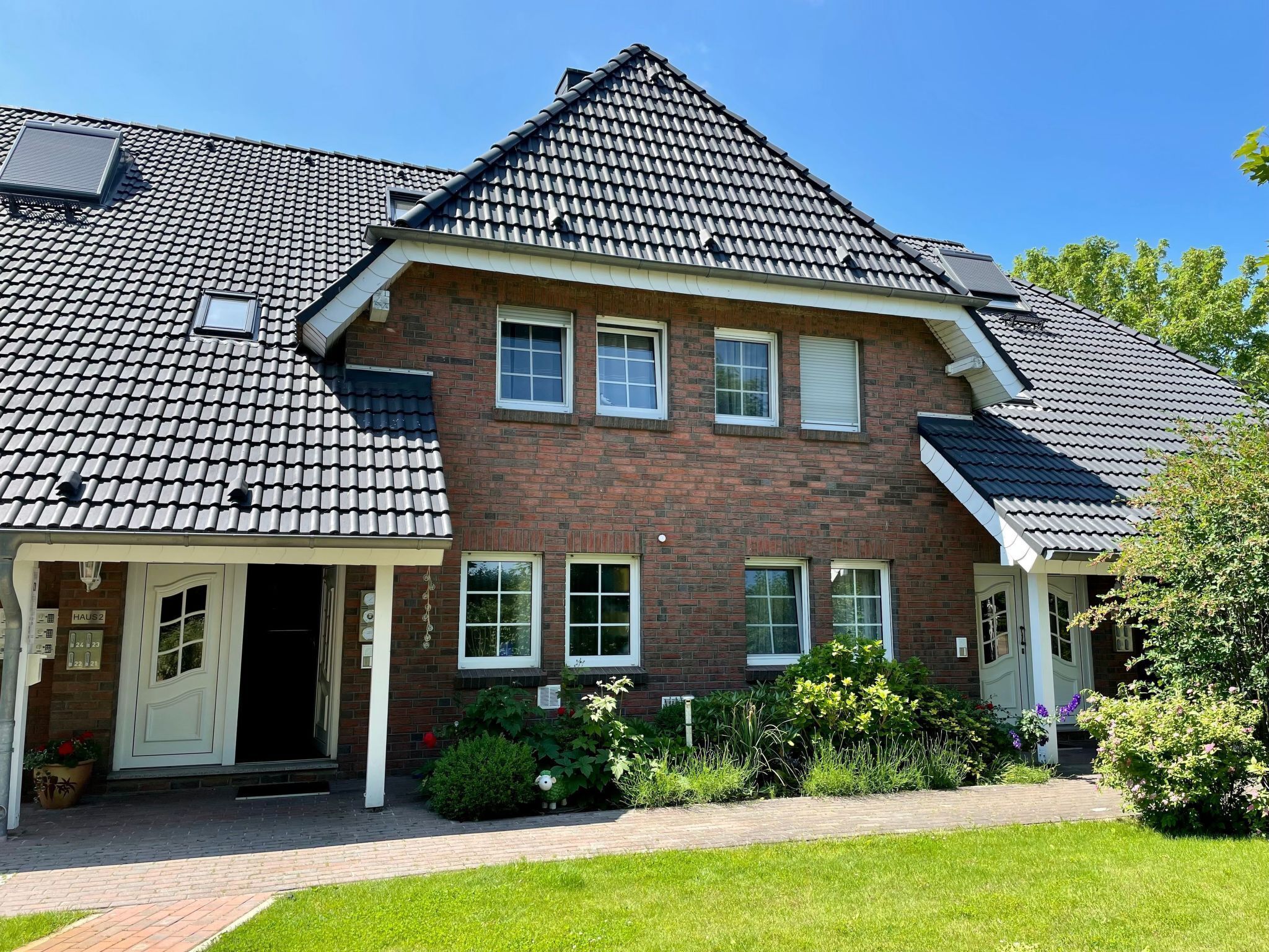 A two-story house with a brick facade, multiple windows, and a sloped roof.
