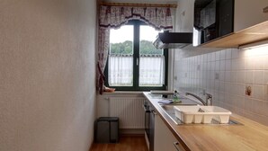 Une petite cuisine avec une fenêtre, un radiateur, un évier et un four à micro-ondes.