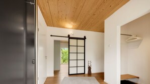 Een modern interieur met een houten plafond, een schuifdeur en uitzicht op een balkon.