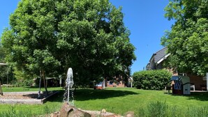 En trädgård med en fontän, en gunga och ett litet lekstuga.
