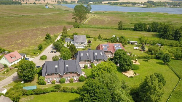 Ett flygbildsbild av ett bostadsområde med hus, en sjö och omgivande åkrar.
