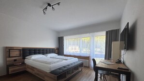 Une chambre moderne avec un lit en bois, un bureau et un téléviseur.