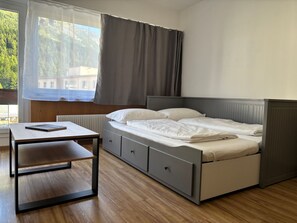 A bedroom with a bed, bedside tables, a window with curtains, and a view of greenery outside. - Chesa In Selva by Interhome (St. Moritz)