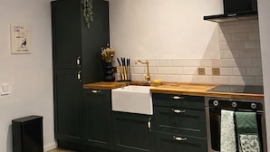 Una cocina moderna con armarios oscuros, encimera de madera, horno empotrado y tragaluz.