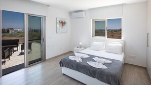 A modern bedroom with a large bed, a glass door leading to an outdoor area, and a painting on the wall. - Geräumiges Ferienhaus für 12 Personen in Paralini by Interhome (Paralimni)