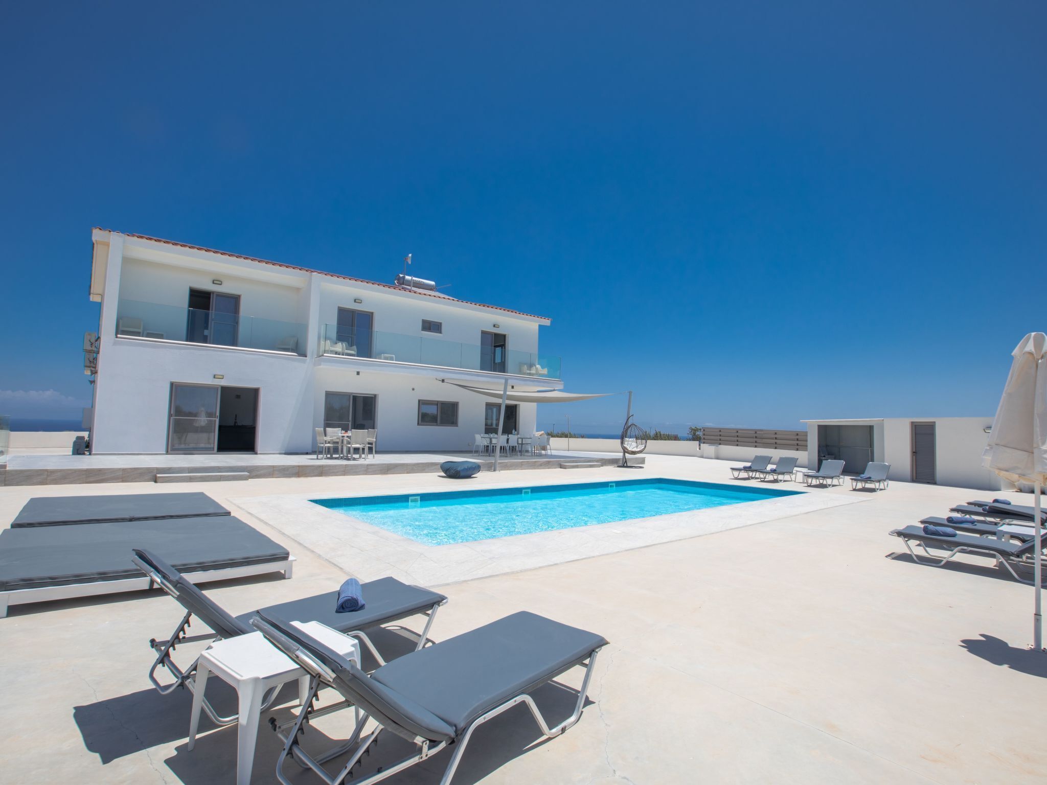A modern two-story building with a rooftop pool area, including sun loungers and a seating area.