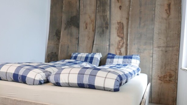 A bed with a wooden headboard and a checkered blanket.