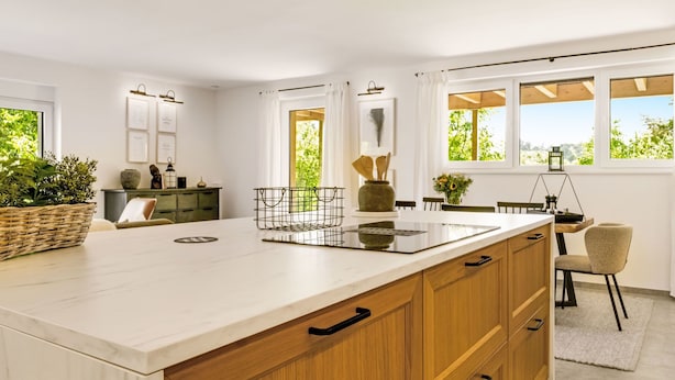 Una cocina moderna con una isla grande, armarios de madera y vistas a zonas verdes.
