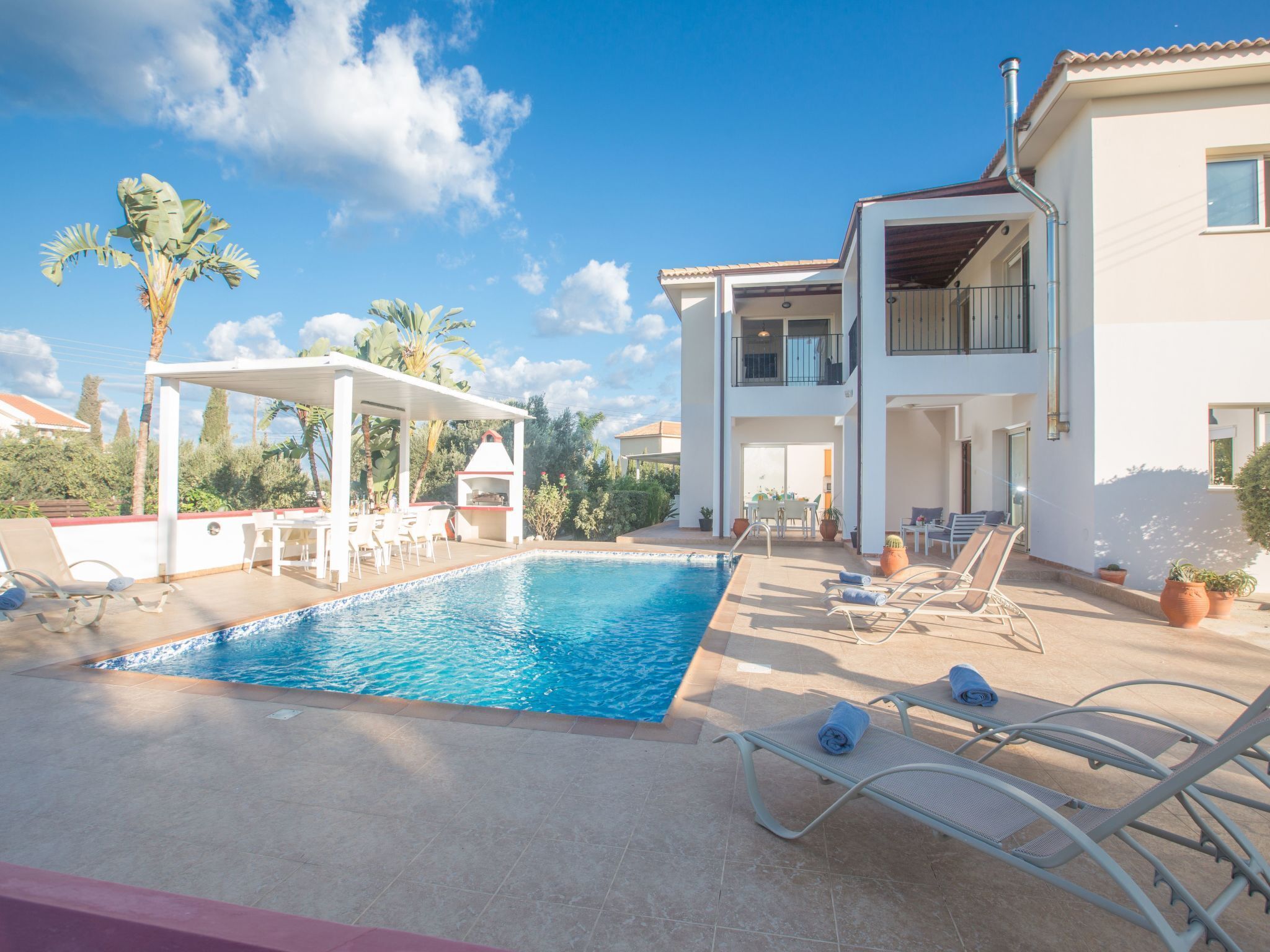 Una casa de dos pisos con piscina, mobiliario de exterior y zona de barbacoa.