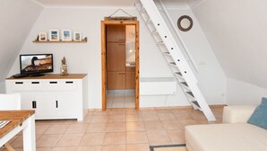 A compact living space with a TV, a wooden cabinet, a staircase, and a white couch. - Carolin by Interhome (Baabe)