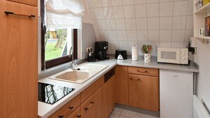 A compact kitchen with a sink, a coffee maker, a microwave, and wooden cabinets. - Carolin by Interhome (Baabe)