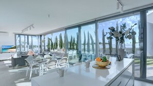 Una cocina moderna con una isla grande, armarios blancos y vista a la playa.