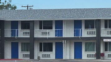 Un motel de varios pisos con una fila de habitaciones, cada una con un balcón y una puerta azul.